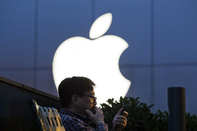  In this Friday, May 13, 2016, file photo, a man uses his mobile phone near an Apple store in Beijing. 