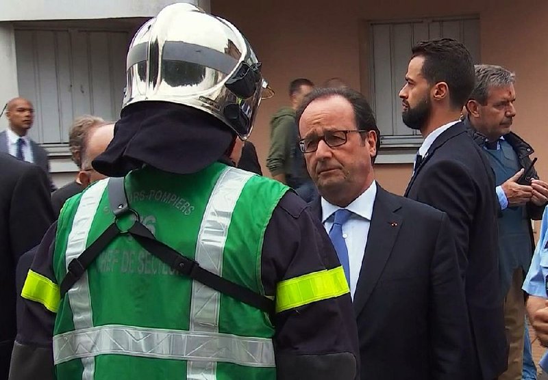 French President Francois Hollande speaks with emergency services personnel Tuesday after arriving at the scene of a church attack in France’s Normandy region.