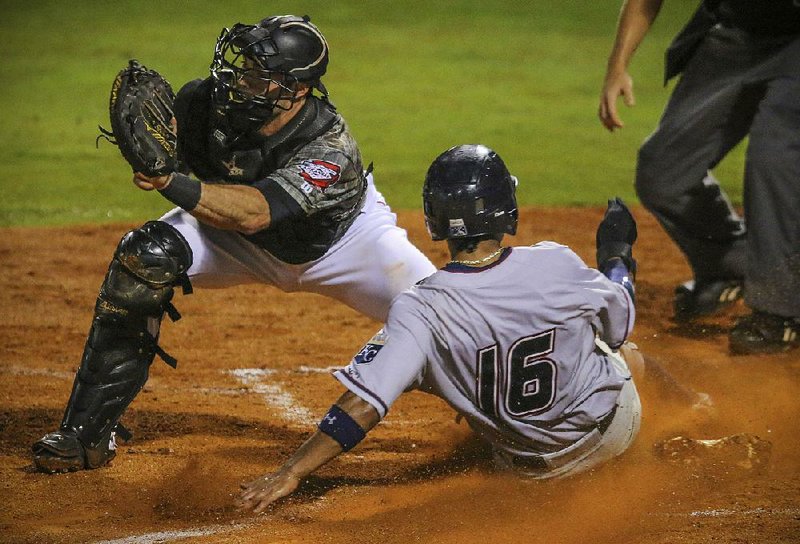 Carlos Garcia (16) of the Northwest Arkansas Naturals slides in ahead of the tag by Arkansas Travelers catcher Wade Wass during Wednesday night’s game in North Little Rock.