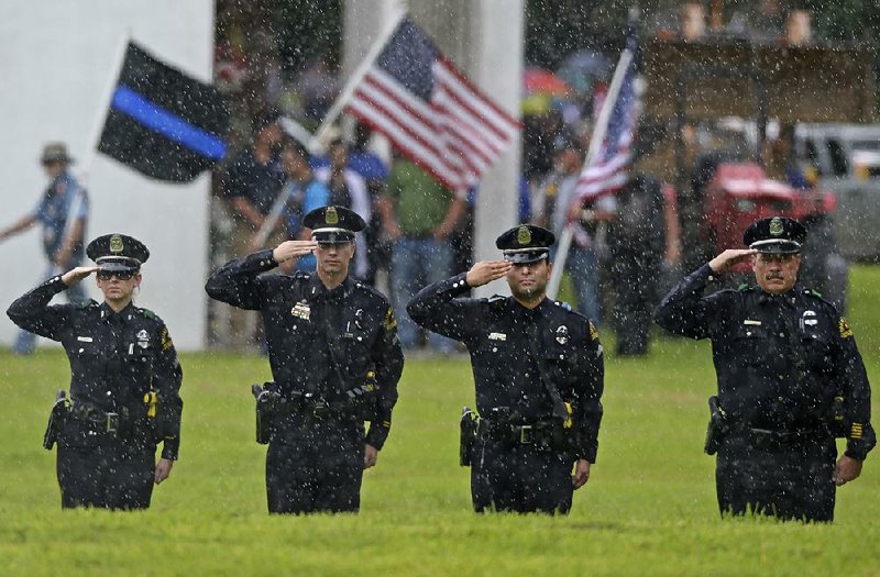 Rain falls Monday as members of the Dallas Police Department salute the casket carrying Baton Rouge police Cpl. Montrell Jackson during funeral services in Baton Rouge. On Wednesday, the National Law Enforcement Officers Memorial Fund reported a sharp rise in the number of shooting deaths of officers compared with the same period last year. 
