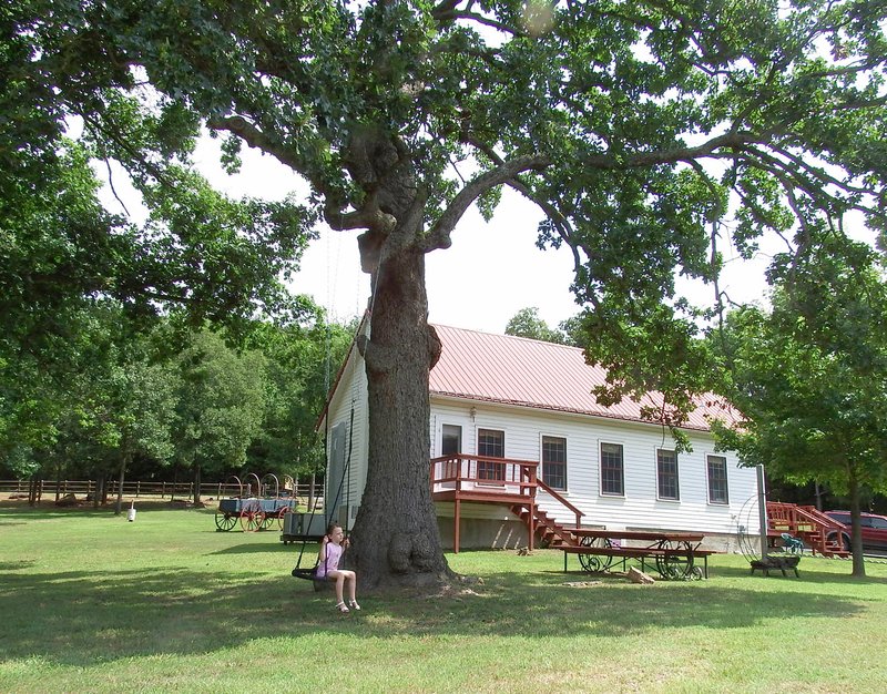 Rue Billingsley, 4, daughter of Rachel and Greg Billingsley of Fayetteville, swings beneath the giant oak tree outside the preserved Coal Gap school building off Slate Gap Road in Garfield. The school, a restored teacher’s cottage and the post office and mercantile building, pays tribute to the once-bustling farming community of Glade.