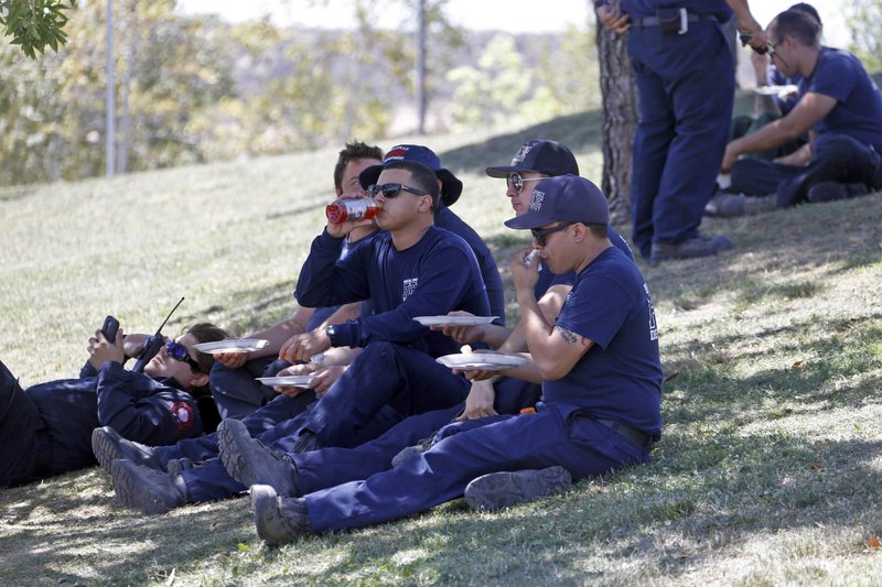 In this Tuesday, July 26, 2016 photo, firefighters eat and rest at a firefighter operations base camp that has been established at Golden Valley High School in Santa Clarita, Calif. 