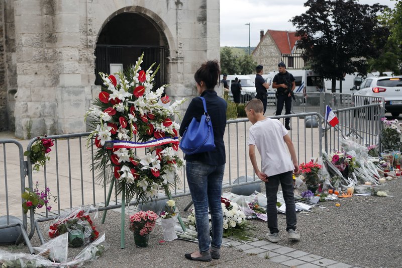 People gather to pay respect with flowers and candles next to the church where an hostage taking left a priest dead the day before in Saint-Etienne-du-Rouvray, Normandy, France, Wednesday, July 27, 2016.