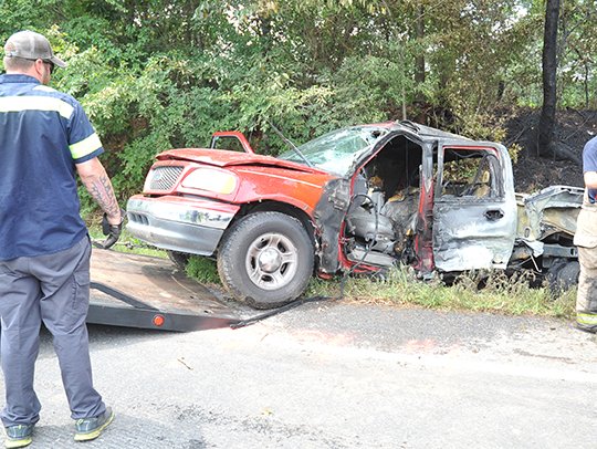 The Sentinel-Record/Mara Kuhn FIERY COLLISION: Emergency personnel remove one of two pickup trucks that collided around 12:30 p.m. Thursday from the north side of the 7000 block of Highway 70 west of Hot Springs.