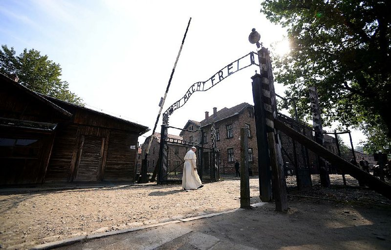Pope Francis walks slowly through the gate of the former Nazi death camp of Auschwitz on Friday in Oswiecim, Poland. The words on the gate say “Work sets you free.” 