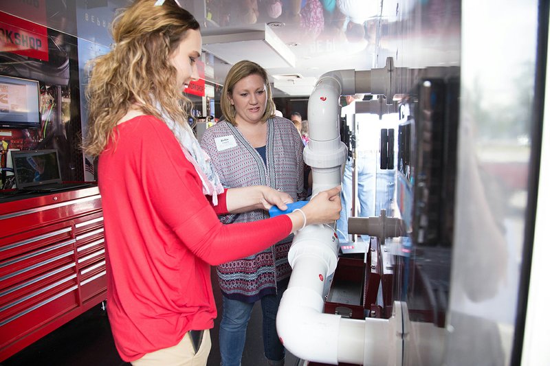 Jessica Capps, left, and Robin English from the Riverview School District practice putting together pipes as part of the plumbing demonstration in the Be Pro Be Proud mobile unit during the Economics Arkansas presentation at Arkansas State University-Beebe