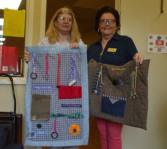 Submitted photo FIDGET QUILTS: Carol Swigart, left, of Hot Springs Area Quilt Guild, and Director Lynn Reeves show two of the donated fidget quilts to be used in activities at The Caring Place.