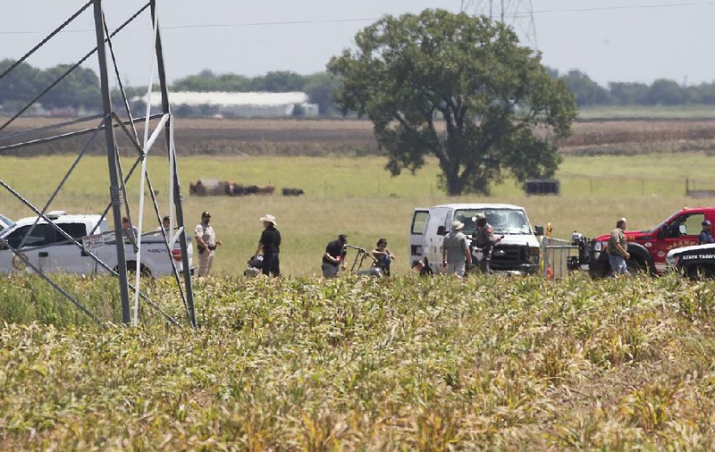 Investigators work Saturday in the fi eld where a hot-air balloon carrying more than a dozen people crashed near Lockhart, Texas.
