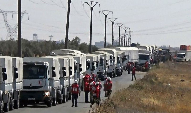 A convoy of the Syrian Arab Red Crescent carries humanitarian aid Saturday to the village of Nawa in southern Syria. As the Syrian government has allowed aid into some besieged areas, it has also opened paths for residents to leave rebel-held areas of Aleppo, the country’s largest city.