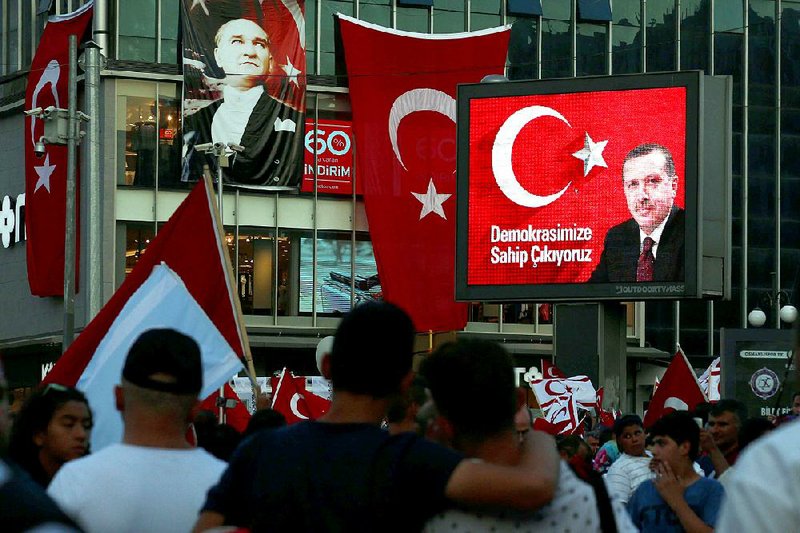 A banner showing Turkey’s independent Republic founder Mustafa Kemal Ataturk (left) and a screen showing current President Recep Tayyip Erdogan adorn Kizilay Square in Ankara on Friday during a pro-government demonstration.