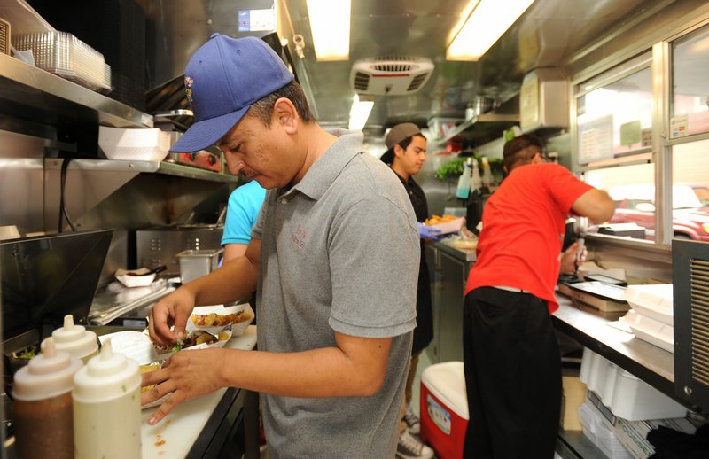 Jesus Rios (left) fills a customer’s order Friday while working at Yeyo’s Mexican Grill west of the Bentonville square. Northwest Arkansas was recently ranked the third best metropolitan statistical area in the country for minority-owned businesses, based on how many there are and how well they perform.