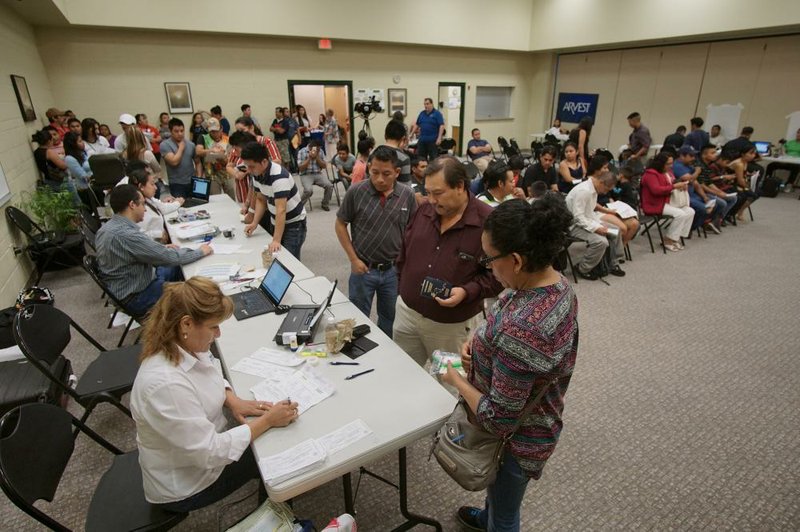 Guatemalans fill out forms and wait in line for ID cards and passports during a mobile consulate event Sunday in Little Rock.