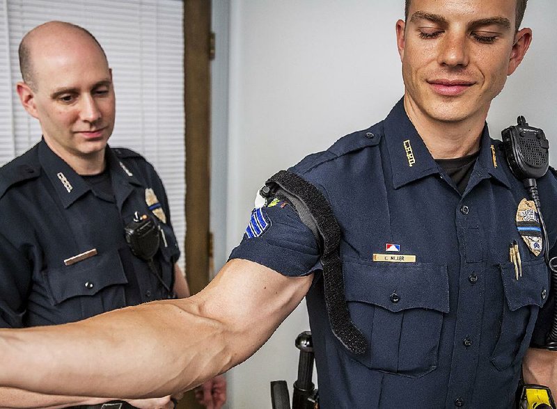 In March 2015, the Little Rock Police Department equipped officers with “blowout” packs that include a tourniquet. Police spokesman Officer Richard Hilgeman (left) demonstrates the tourniquet on Sgt. Cody Miller’s arm.