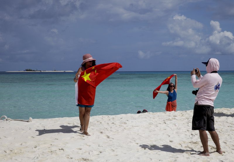 In this Sept. 14, 2014 file photo, Chinese tourists take souvenir photos with the Chinese national flag as they visit Quanfu Island, one of Paracel Islands of Sansha prefecture of southern China's Hainan province in the South China Sea.