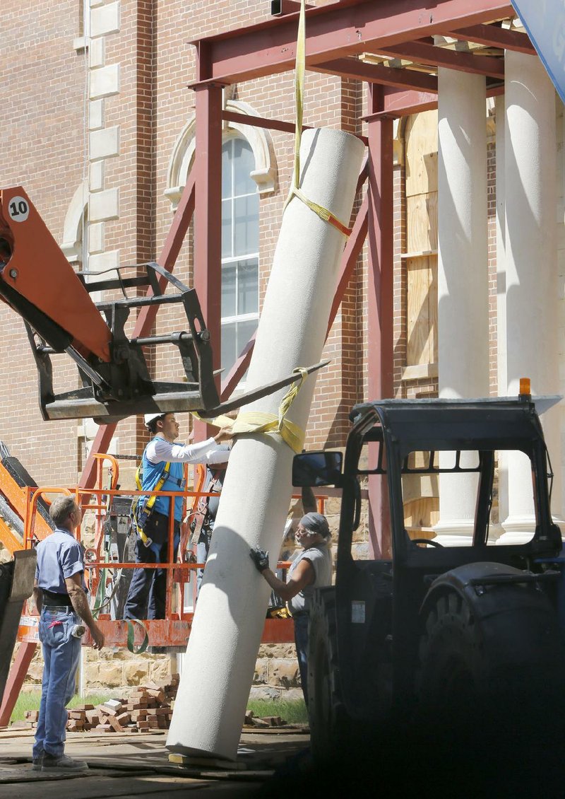 Workers place the last of four columns into position Monday at the east entrance of Old Main on the campus of the University of Arkansas at Fayetteville. The original columns were from 1875.
