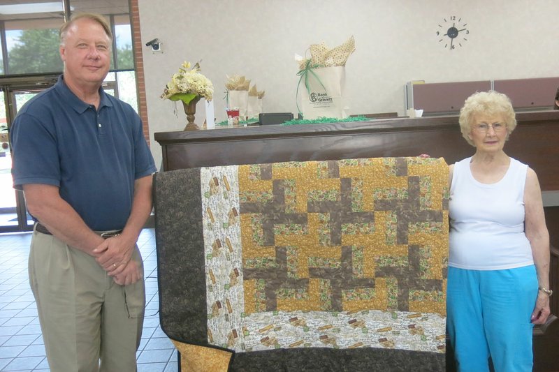 Photo by Susan Holland Betty Howard, right, is shown with the basket-weave pattern quilt she donated to the Gravette Kiwanis Club to be raffled off at its pancake breakfast on Gravette Day. Accepting the quilt is Kiwanis president Richard Page, superintendent of Gravette schools. The quilt is on display at the Bank of Gravett and later will be displayed at Arvest Bank. Tickets can be purchased at either bank. All proceeds will go toward Kiwanis service projects.