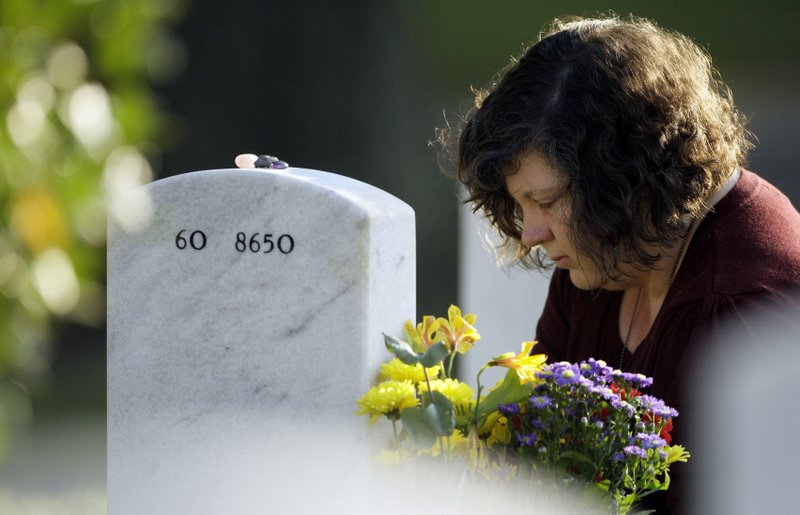 FILE - In this Sept. 15, 2009 file photo, Ami Neiberger-Miller, whose brother Army Spc. Christopher Neiberger was killed in Iraq in 2007, visits her brother's grave at Arlington National Cemetery in Arlington, Va. 