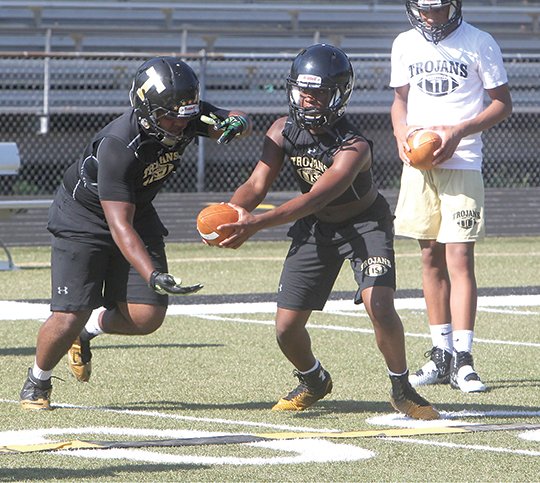 The Sentinel-Record/Richard Rasmussen HOT FOOTBALL: Hot Springs running back Colby Wallace, left, takes a handoff from quarterback Aaron Williams, center, during the first day of fall practice Monday at Reese Memorial Stadium. Most teams practiced in the morning before a heat advisory went into effect Monday afternoon, but Garland County players could be dealing with hot, muggy temperatures their first week of camp, according to the National Weather Service.