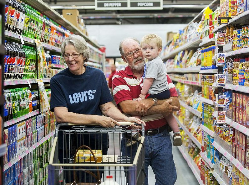 Charlene and Jerry Yingst shop with their grandson Jaxon Blakeslee on Wednesday at the Harps Food Store in Gravette. The store, formerly a Wal-Mart Express, reopened Wednesday. 