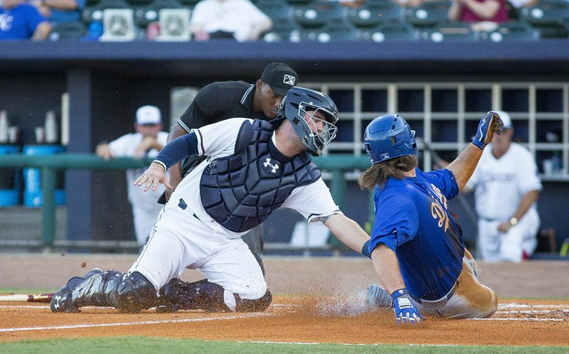 Catcher Cam Gallagher of the Northwest Arkansas Naturals (left) tags out Joey Curletta of the Tulsa Drillers on Thursday in the second inning at Arvest Ballpark in Springdale.