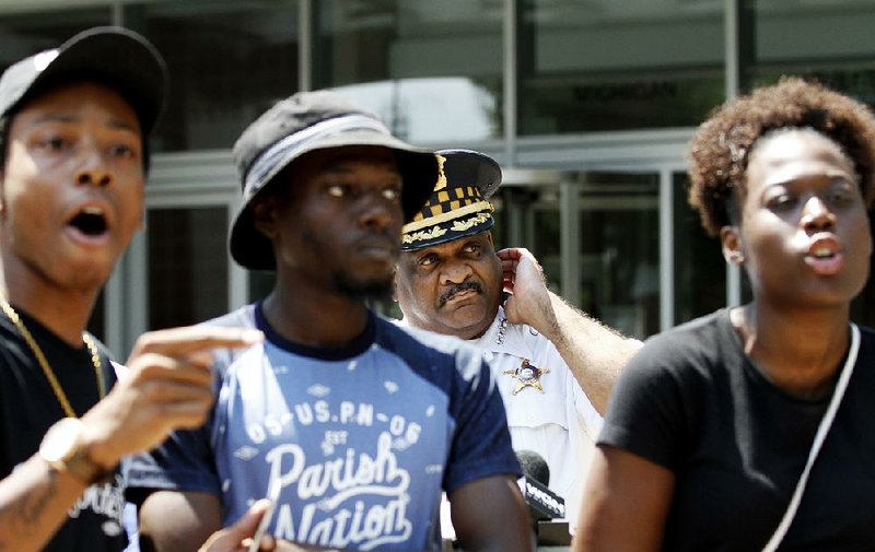 Chicago police Superintendent Eddie Johnson is blocked Friday by three protesters as he tries to deliver a written statement to journalists gathered outside police headquarters.