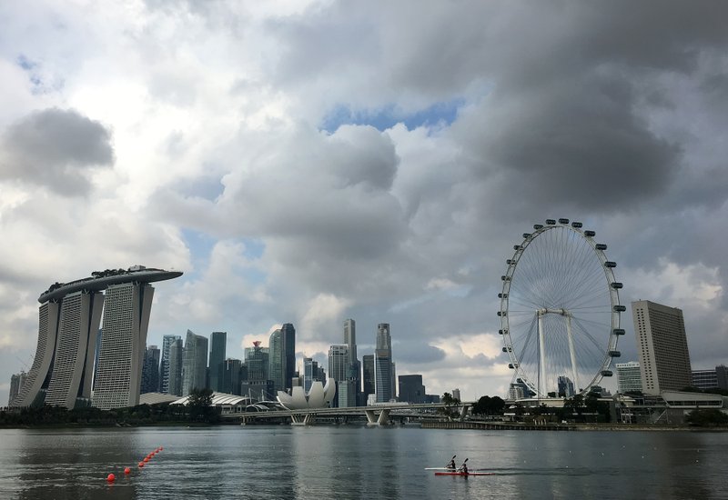 In this Wednesday, April 20, 2016, file photo, two kayaks are dwarfed against the skyline of the Marina Bay area, which is home to popular hotels, and tourist attractions such as the Singapore Flyer, the city-state's observation wheel seen at right, in Singapore. 
