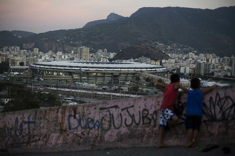 From their vantage point Friday in the Mangueira slum in Rio de Janeiro, two boys look toward the gleaming Maracana Stadium, a focal point of the 2016 Summer Olympics in Brazil. 