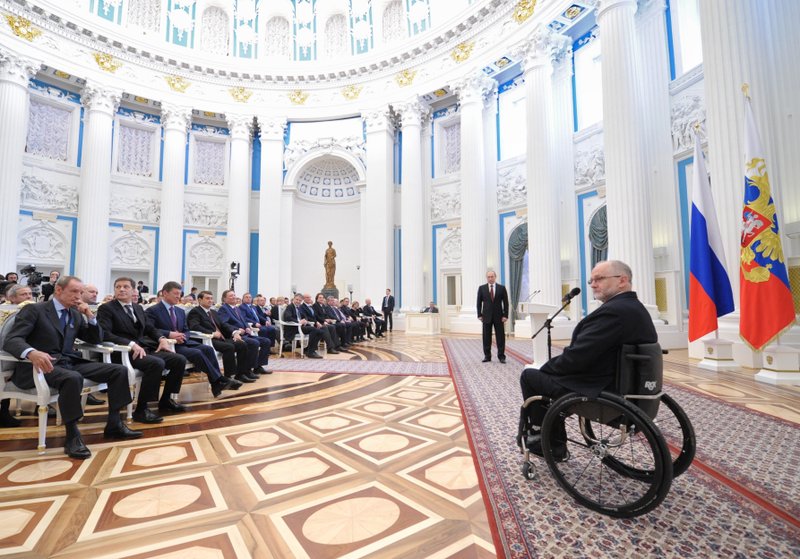FILE - In this file photo taken on Monday, March 24, 2014, Sir Philip Craven, President of the International Paralympic Committee, right, speaks as Russian President Vladimir Putin, standing background center, listens to him during an awards ceremony in the Kremlin in Moscow, Russia. 