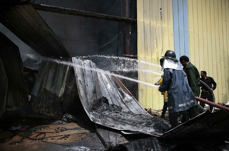 Firefighters work to extinguish a fire at a food factory hit by Saudi-led airstrikes in Sanaa, Yemen, on Tuesday.