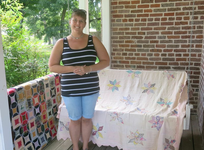 Photo by Susan Holland Erin McVittie posed on the front porch of the Gravette Historical Museum with some of the vintage quilts which are in the museum&#8217;s collection. McVittie took over the duties of museum curator last week and has announced the museum will be open all day on Gravette Day, Saturday, Aug. 13. She invites all to come and tour the Kindley home and annex that day. Regular hours for the museum will be Thursday, Friday and Saturday, 11 a.m. to 3 p.m.