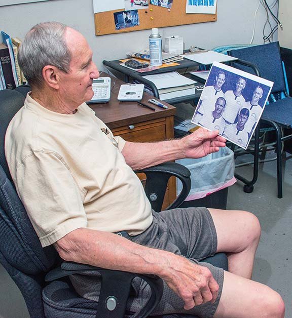 Former Conway Wampus Cats football coach and athletic director Dennis Fulmer looks at a photo of his 1968 Conway High School coaching staff after realizing they have all been inducted into halls of fame. Those hall-of-famers include Johnny Simmons, Ernie Miller, Joe Fred Young and Bernie Cox.