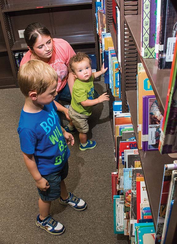 Supporters of the effort to establish a charter school in the Paron community reminisced at the former Paron Elementary School. Carlie Carreon helps her son, Brantley Carreon, 1, and her friend’s son, Jase Rostan, 3, as they look through some books left in the old school library.