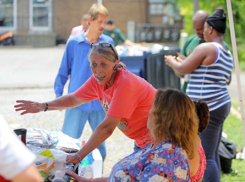 Rhonda Martinez, who runs a pet ministry for the homeless through her church — Lakewood United Methodist in North Little Rock — talks with volunteers at From His Throne Ministries, a church that provides meals and ministers to the homeless. 