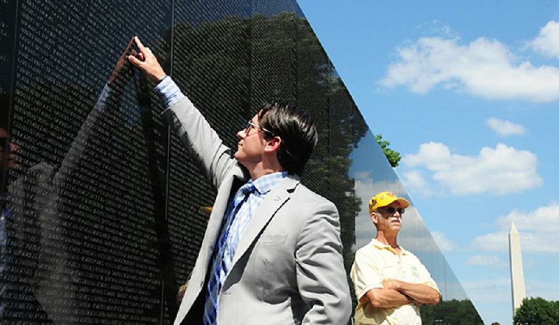 Andrew Brennan, a former Army captain who served as a pilot in Afghanistan, points to the name of a cousin on the wall of the Vietnam Veterans Memorial.