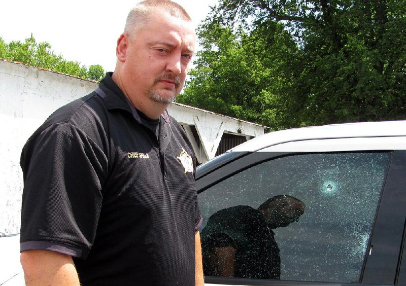 Hackett Police Chief Darrell Spells escaped with only a fl esh wound in his left temple Wednesday when a bullet pierced the driver’s-side window of his official SUV. The chief says he counted seven to nine bullet holes in his vehicle after the standoff with Billy Jones.