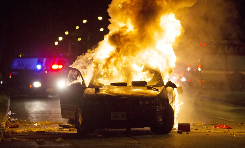 A car burns as a crowd of more than 100 people gathers following the fatal shooting of a man in Milwaukee Saturday. The Milwaukee Journal Sentinel reported that officers got in their cars to leave at one point, and some in the crowd started smashing a squad car's window, and another vehicle, pictured, was set on fire. The gathering occurred in the neighborhood where a Milwaukee officer shot and killed a man police say was armed hours earlier during a foot chase. 