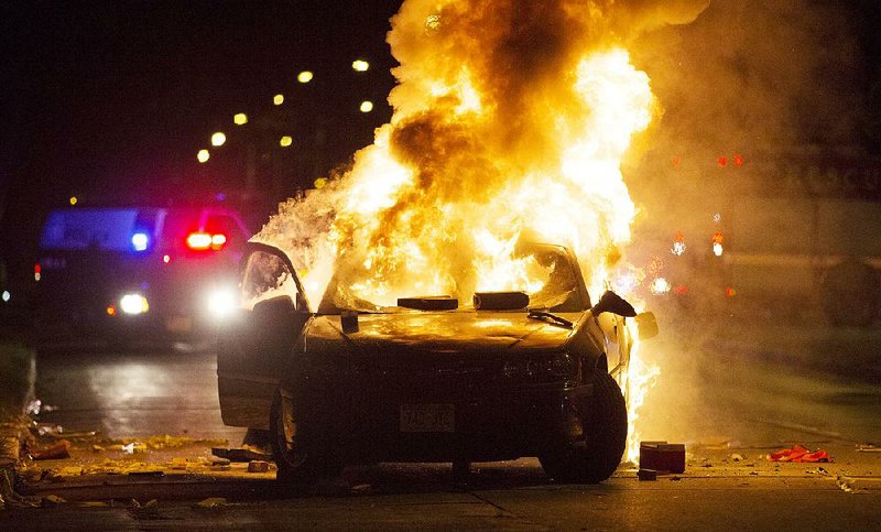 A car burns Saturday night in Milwaukee as a crowd gathers after the fatal shooting of a man police say was armed.