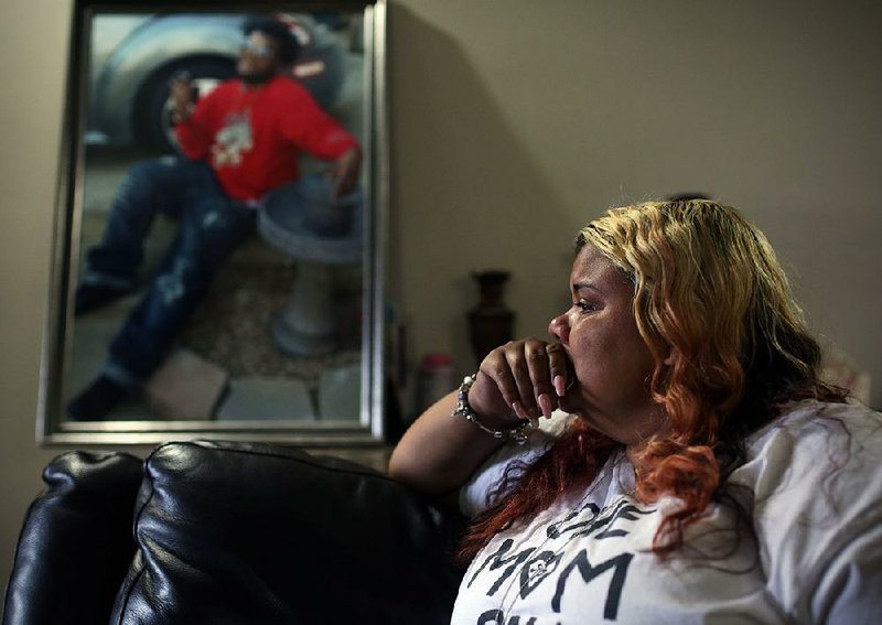 Loretta Lent looks out her front door as she composes herself Saturday while talking about her son, Junius Pitts Jr. (in photo), who died in a shooting in January and whose case is one of seven homicides this year in which Little Rock police have made no arrests.