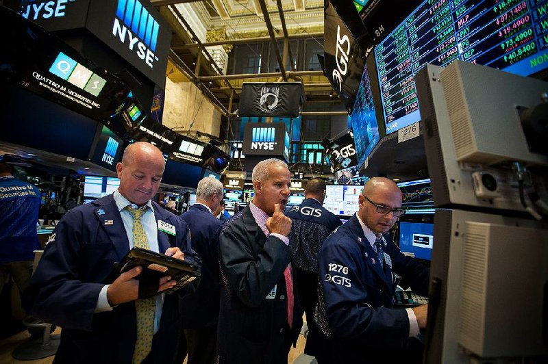 Traders work Monday on the fl oor of the New York Stock Exchange.