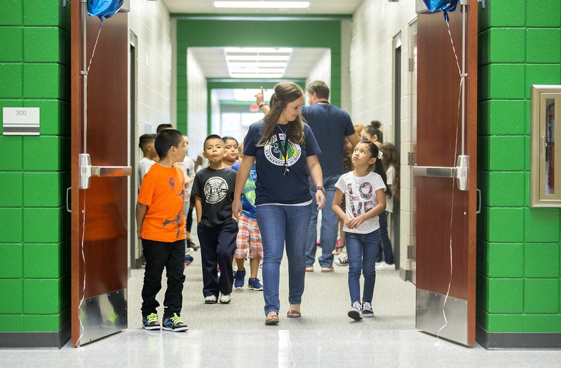 Catrina Anderson, second-grade teacher, walks Monday with her students through the halls at Knapp Elementary School in Springdale. Monday was the first day for students.