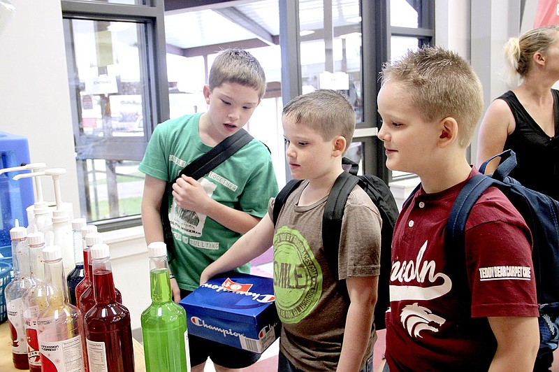 LYNN KUTTER ENTERPRISE-LEADER Jack Whitaker, left, 11, Travis Whitaker, 9, and Charlie Whitaker, 7, are ready for school with new backpacks and new tennis shoes. But more importantly at this moment, they are deciding on what flavor snowcone they want. The brothers attend school in Lincoln. See more photos on Page 7A.