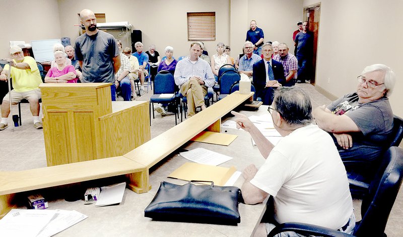 Garfield resident Scott Wasseman, standing a the podium, listens to alderman Bill Mathew, as alderman Dale Watkins, and the crowd attending the Aug. 9 City Council meeting, listen. Wasserman, during the public comments section of the meeting, chastised city government for &#8216;Negativity, negativity, negativity.&#8217;