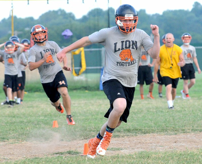 Photo by Flip Putthoff Gravette Lions high school football players run drills Tuesday, Aug. 9, during practice at Gravette High School.