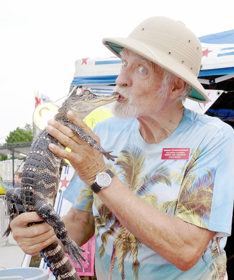 Rita Greene/McDonald County Press Ken Henderson, the Alligator Man, kisses one of his alligators, Spike, at Jesse James Days in Pineville Aug. 10-13.