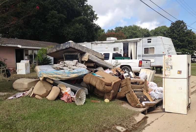 A growing pile of debris sits outside the flood-ravaged home of Carolyn and James Smith in Denham Springs, La. on Wednesday, Aug 17, 2016. Smith says she and four other adults will live for the time being in the travel trailer that one of her sons towed to the driveway after weekend flooding inundated the area. (AP Photo/Kevin McGill)
