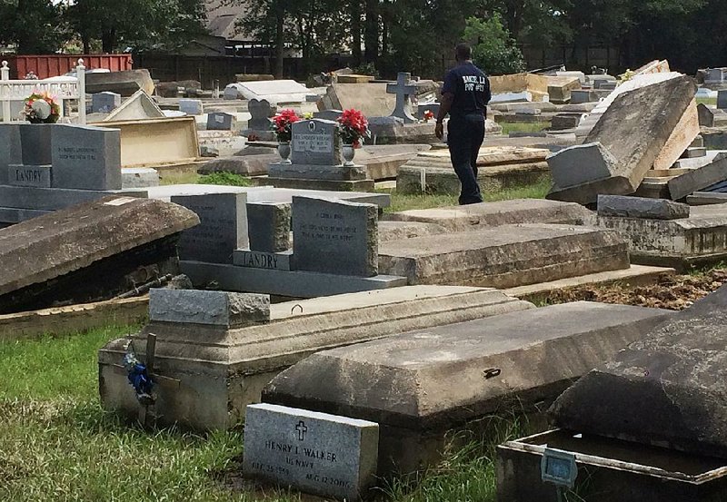 Willie Brooks on Thursday walks through the fl ood-damaged Plainview Cemetery in Denham Springs, La. Flooding this week has added to the troubles — including racial unrest — Louisiana has experienced in the past few weeks. But now Louisianians say they are pulling together.