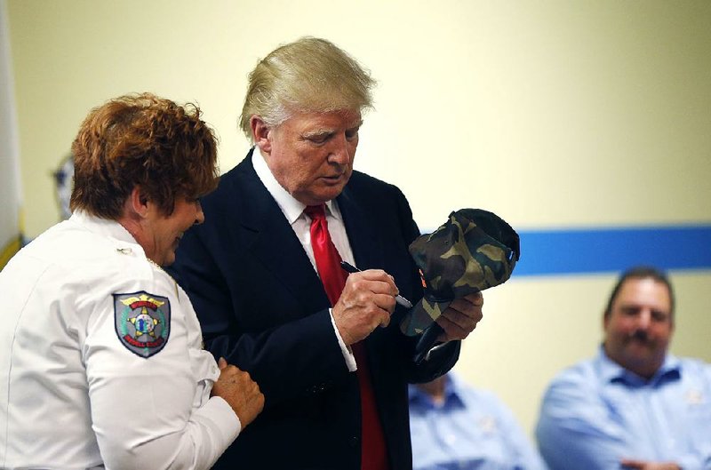 Donald Trump autographs a hat as he speaks at a Fraternal Order of Police lodge during a campaign stop Thursday in Statesville, N.C.