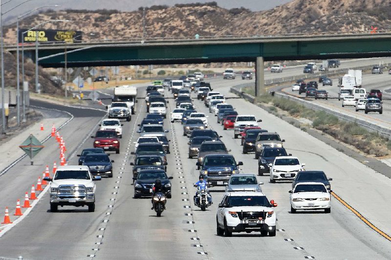 California Highway Patrol troopers lead vehicles south on Interstate 15 as those lanes opened Thursday in the Cajon Pass after a wildfire closed the interstate this week.