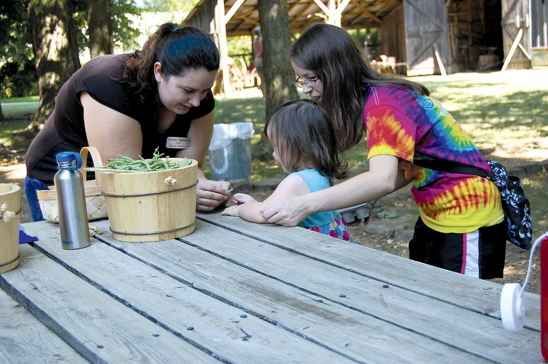 Education assistant Carly Squyres helps kids string leather britches at the Shiloh Museum of Ozark History.