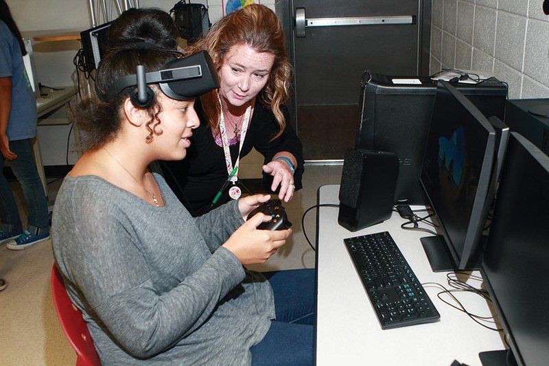 Ahlf Junior High School EAST facilitator Kelly Martin, right, shows eighth-grader Emon Redmann how to wear the Oculus Rift equipment that was given to the school as part of its new EAST Initiative program that began this school year. Oculus Rift is a virtual-reality headset that allows students to take virtual tours.